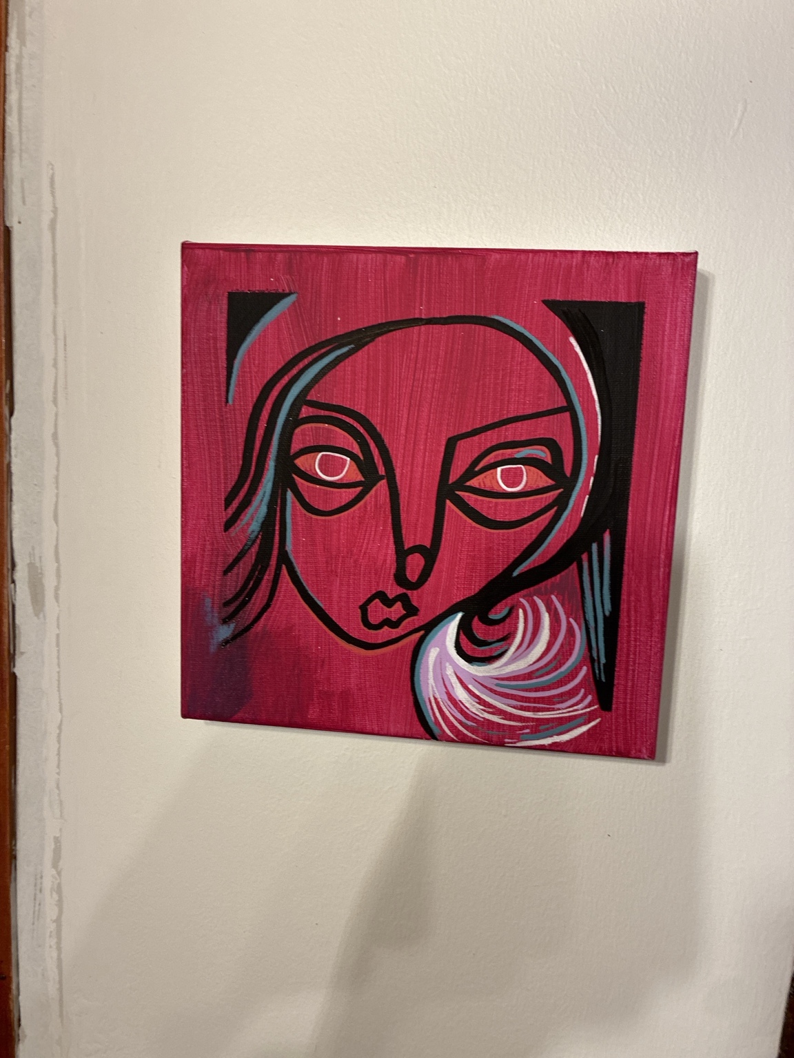 Rostro de contornos negros sobre magenta, con ojos delineados en blanco y trazos celestes.
